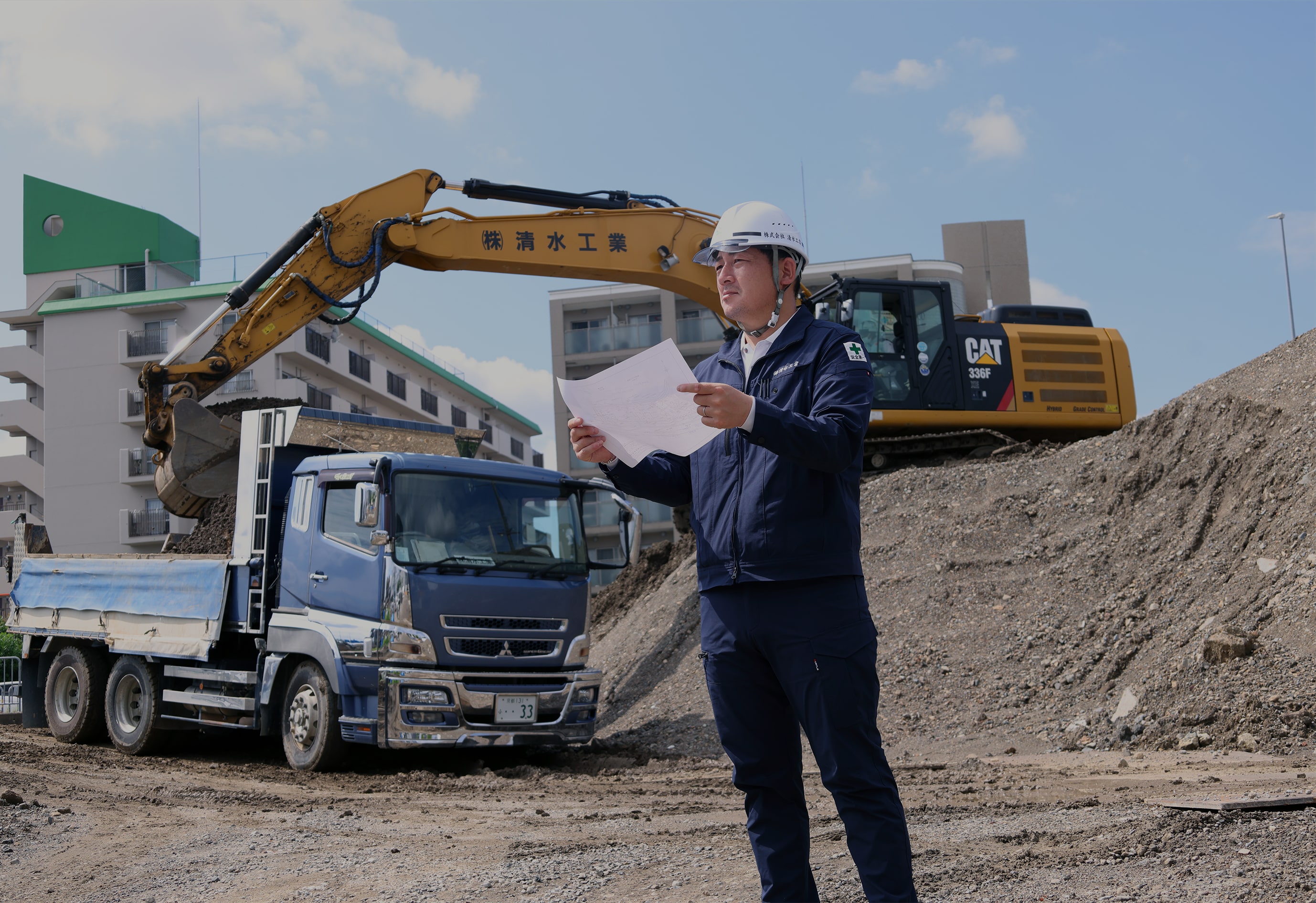 ヘルメットを被った中年男性が図面をみている