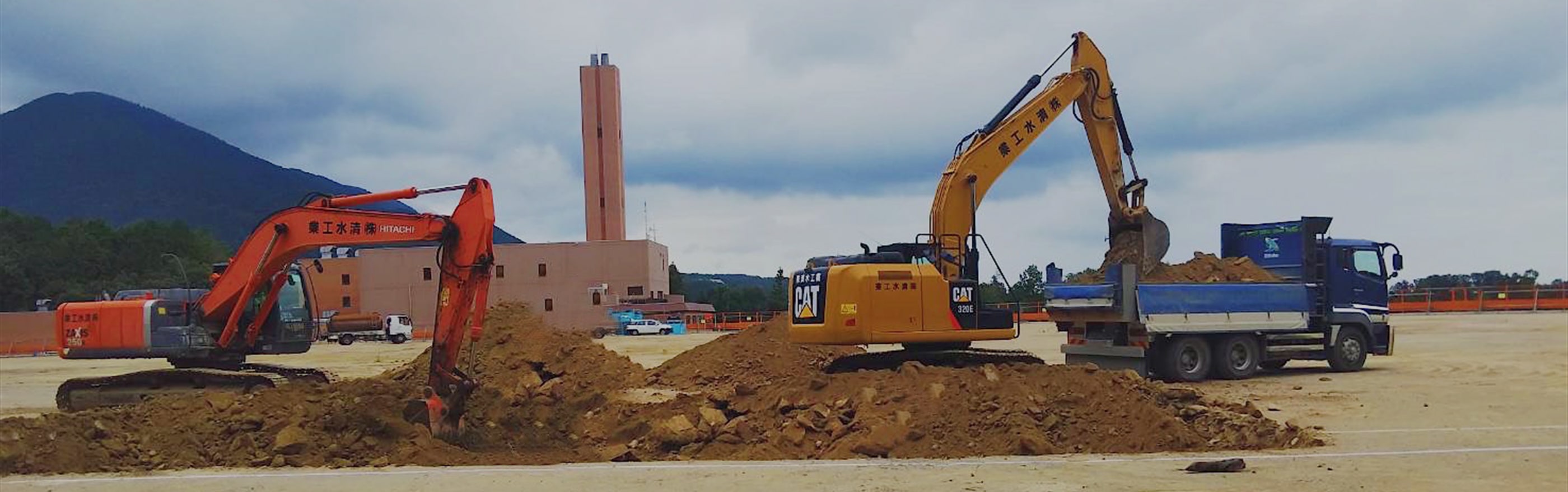 重機で土をトラックの積み荷に運んでいる