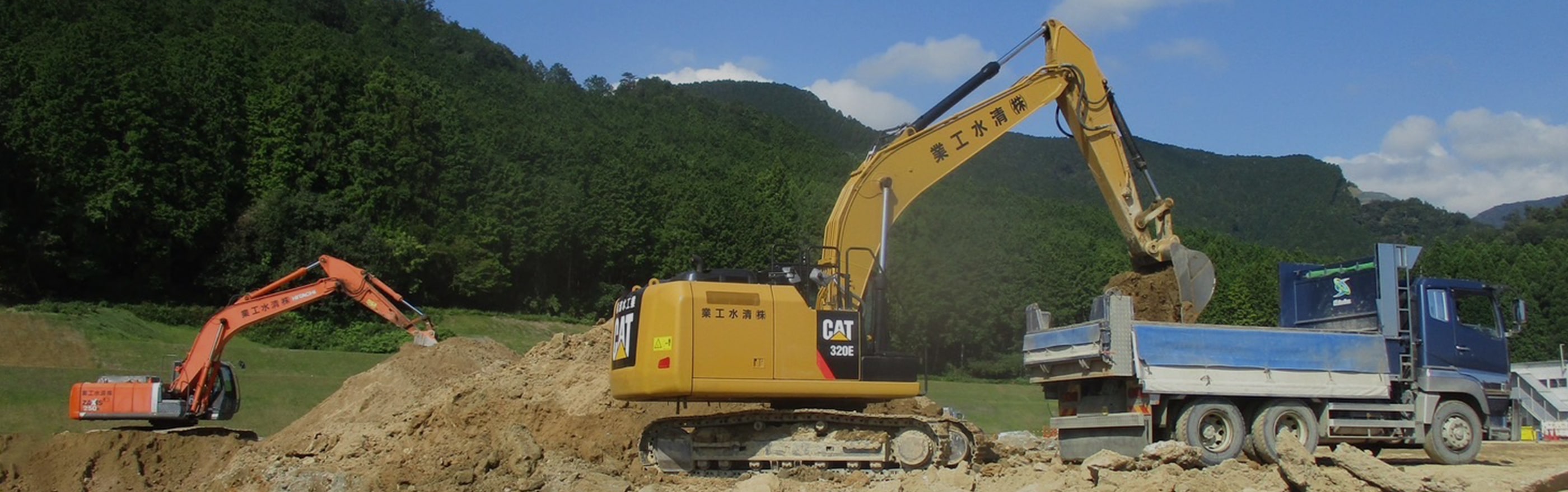 重機で土をトラックの積み荷に運んでいる