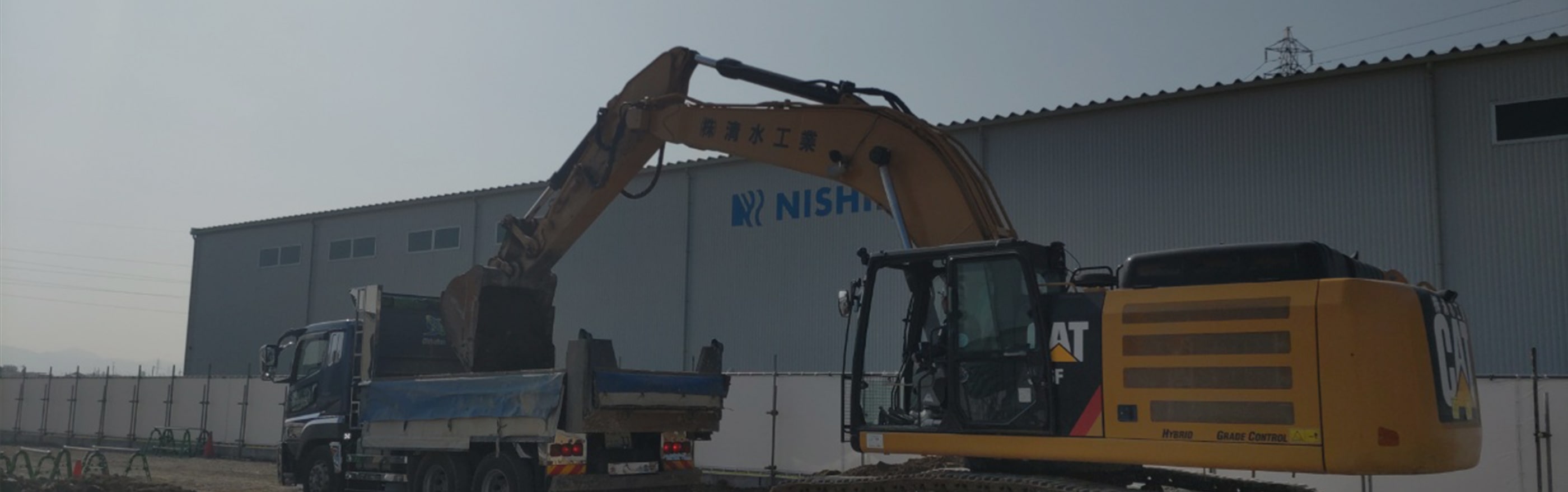 重機で土をトラックの積み荷に運んでいる