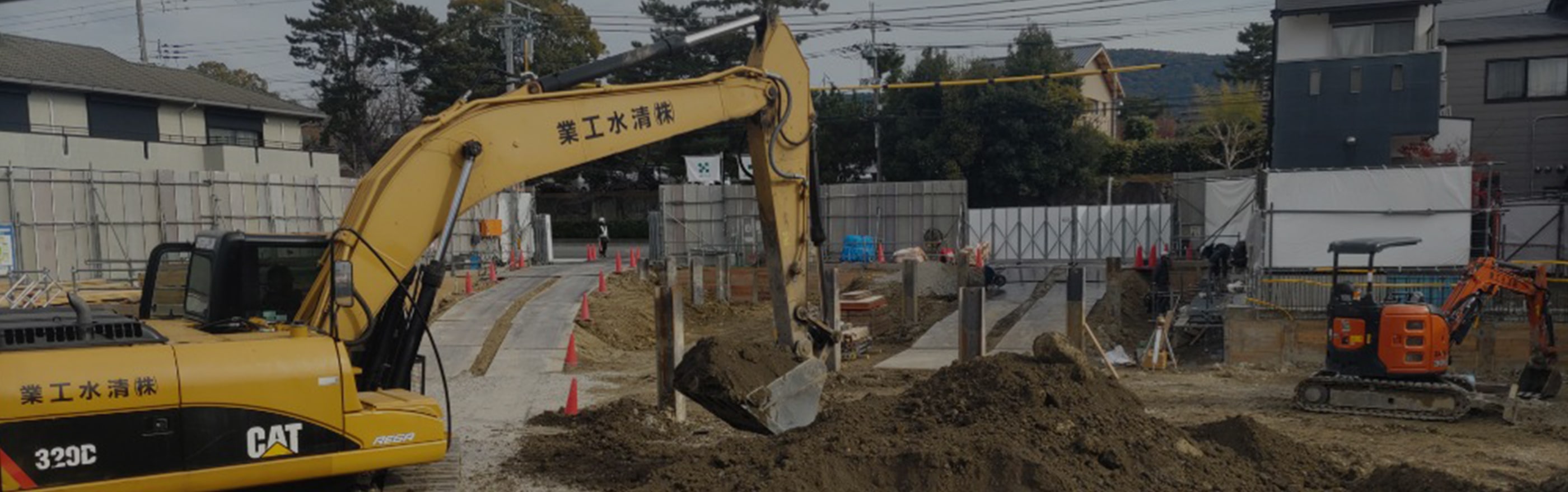 工事現場で黄色の重機が土を運んでいる