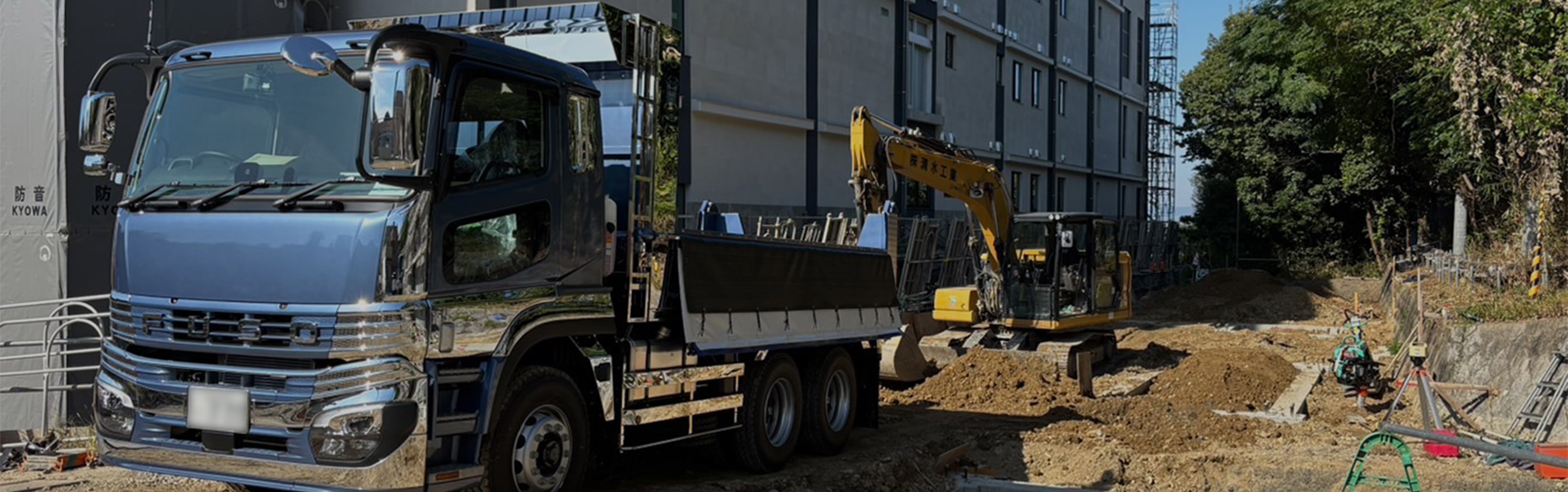 青いトラックと黄色の重機が並んでいる
