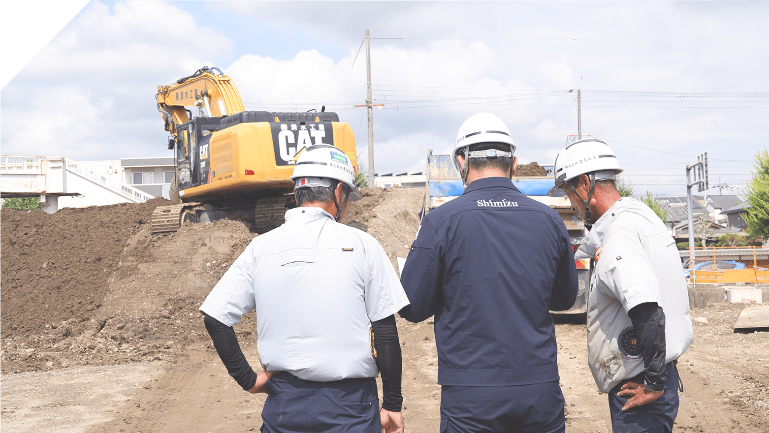 作業現場で３人の従業員が話し合っている様子