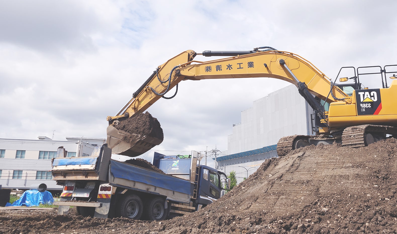 重機でトラックに土を運んでいる様子
